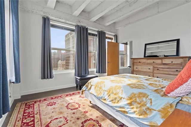 bedroom featuring multiple windows, beam ceiling, and baseboards