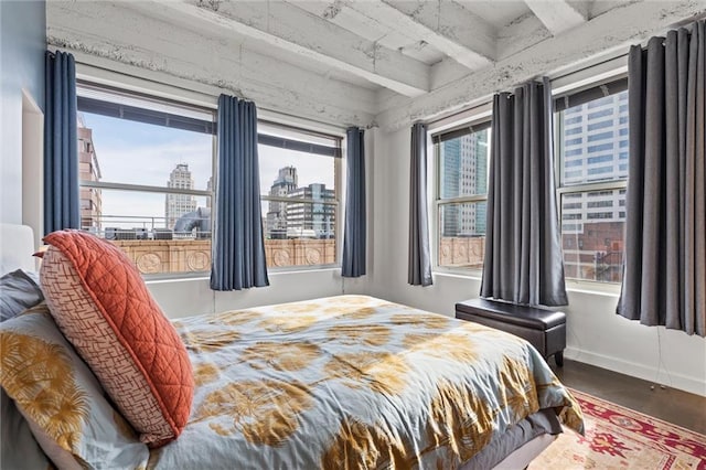 bedroom featuring beam ceiling, a city view, and baseboards