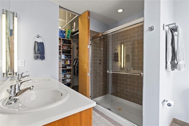 bathroom with double vanity, a shower stall, a walk in closet, and a sink