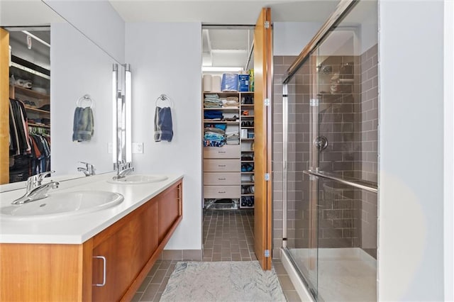 bathroom featuring a shower stall, a walk in closet, a sink, and tile patterned floors