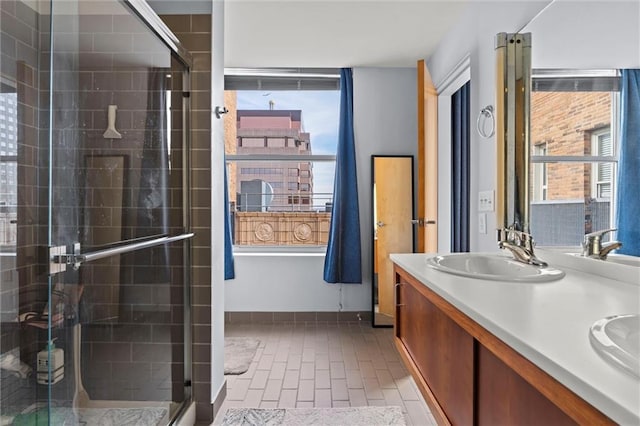 bathroom with a healthy amount of sunlight, a stall shower, double vanity, and a sink