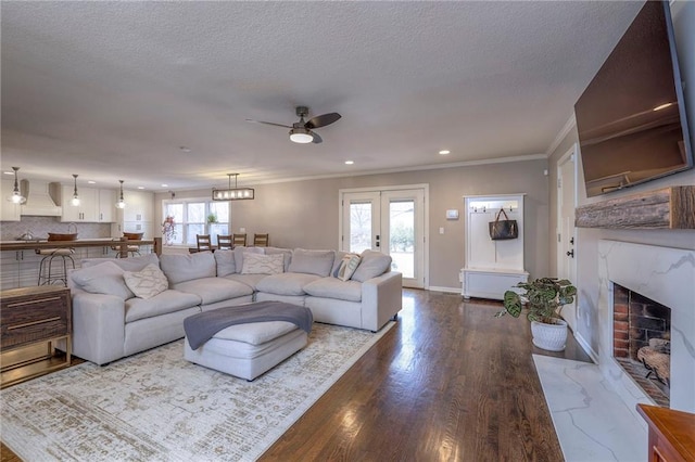 living room with a fireplace, ornamental molding, wood-type flooring, a textured ceiling, and french doors