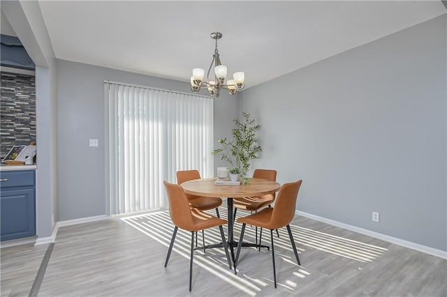 dining room with light wood-type flooring and an inviting chandelier