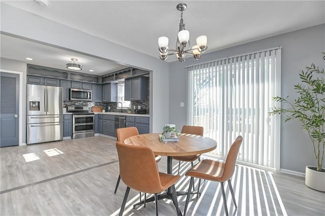 dining room featuring a notable chandelier, light hardwood / wood-style floors, and sink