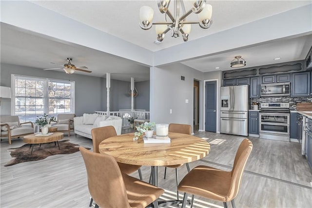 dining area with light hardwood / wood-style floors and ceiling fan with notable chandelier