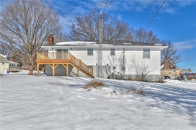 snow covered rear of property featuring a deck and a garage