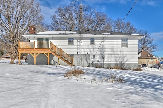 snow covered house featuring a deck and a garage