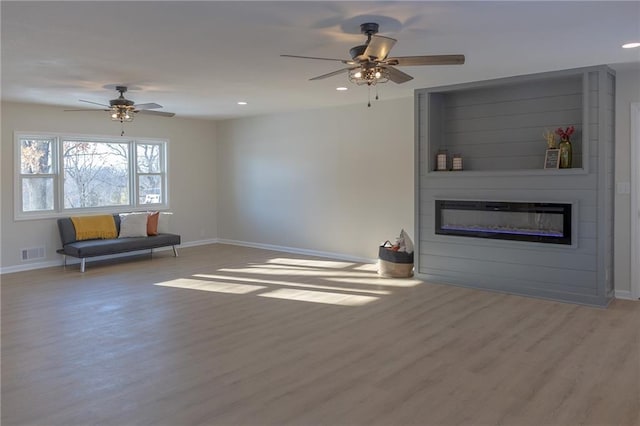 unfurnished living room featuring a fireplace, ceiling fan, and light wood-type flooring