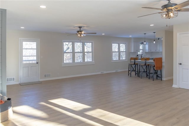 living room featuring ceiling fan, a wealth of natural light, and light wood-type flooring