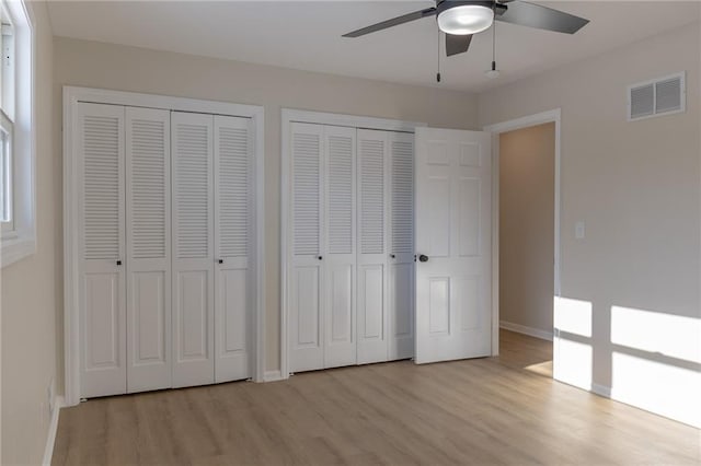 unfurnished bedroom with multiple closets, ceiling fan, and light hardwood / wood-style floors