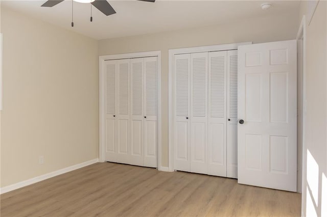 unfurnished bedroom with ceiling fan, light hardwood / wood-style floors, and multiple closets