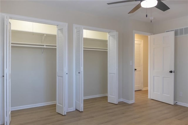 unfurnished bedroom featuring multiple closets, ceiling fan, and light wood-type flooring