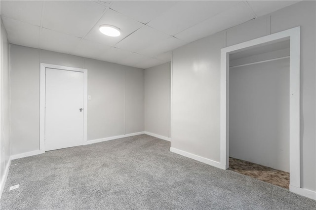 unfurnished bedroom featuring carpet floors, a closet, and a paneled ceiling