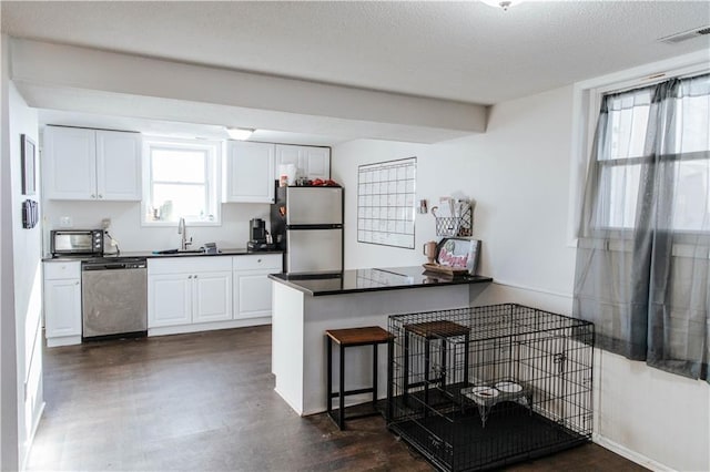 kitchen with kitchen peninsula, sink, white cabinetry, appliances with stainless steel finishes, and a kitchen breakfast bar