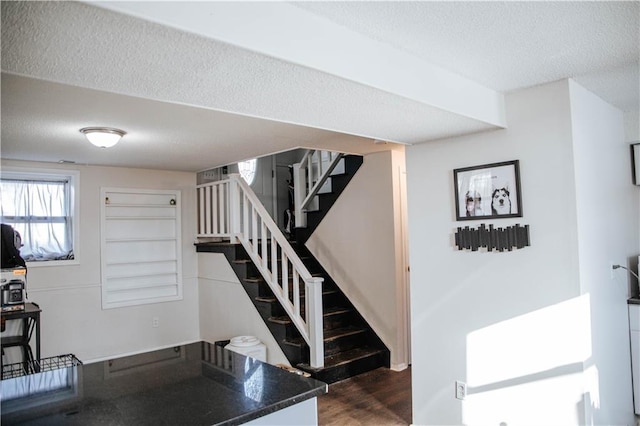 staircase featuring wood-type flooring and a textured ceiling