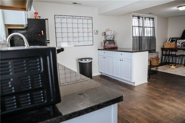 kitchen with white cabinetry, stainless steel fridge, and dark hardwood / wood-style flooring