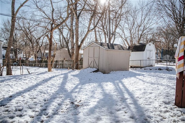 yard layered in snow featuring a shed and a trampoline