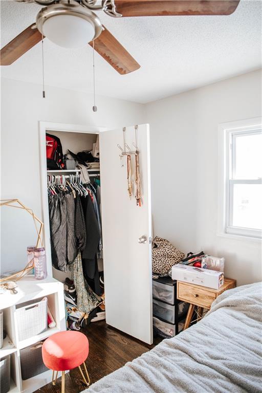 bedroom with a textured ceiling, ceiling fan, a closet, and dark hardwood / wood-style floors