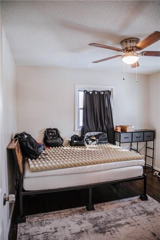 bedroom featuring ceiling fan, a textured ceiling, and dark hardwood / wood-style flooring