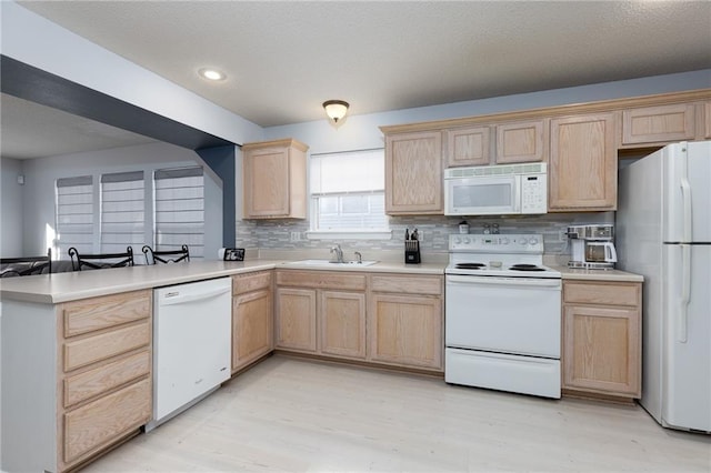 kitchen with sink, white appliances, tasteful backsplash, light brown cabinetry, and kitchen peninsula