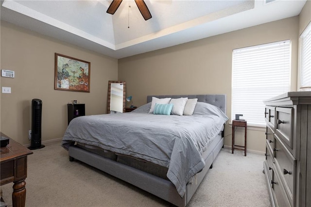 carpeted bedroom with ceiling fan and a raised ceiling