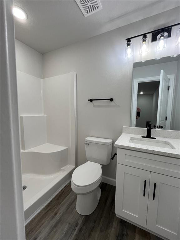 bathroom featuring walk in shower, vanity, wood-type flooring, and toilet