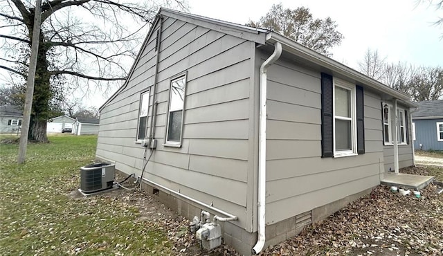 view of side of home featuring a lawn and central AC