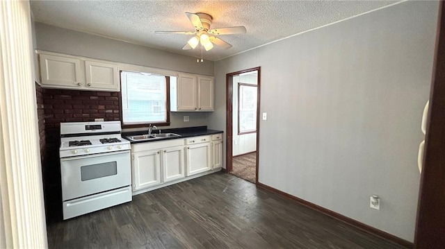 kitchen with a textured ceiling, white gas range oven, dark hardwood / wood-style flooring, white cabinets, and sink