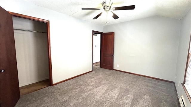 unfurnished bedroom featuring vaulted ceiling, a closet, a baseboard heating unit, carpet flooring, and ceiling fan