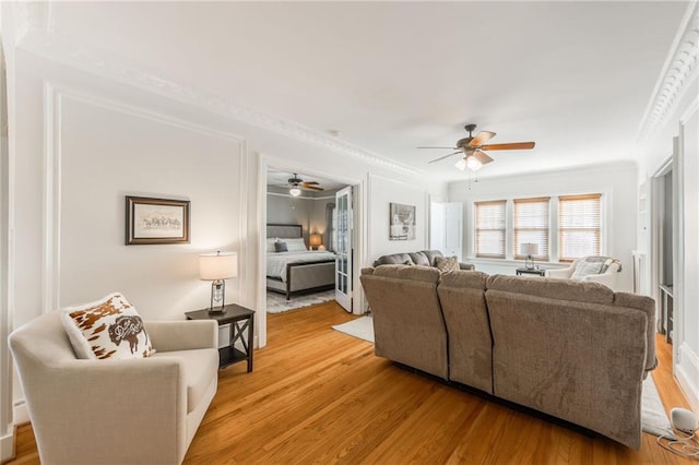 living room featuring light wood-type flooring, ceiling fan, and ornamental molding