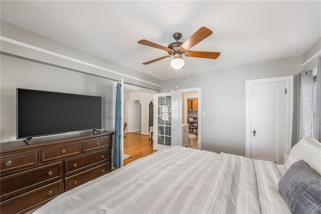 bedroom with ceiling fan, ensuite bathroom, and light hardwood / wood-style flooring