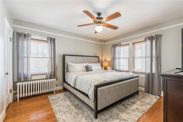 bedroom featuring ceiling fan, radiator, and light hardwood / wood-style flooring