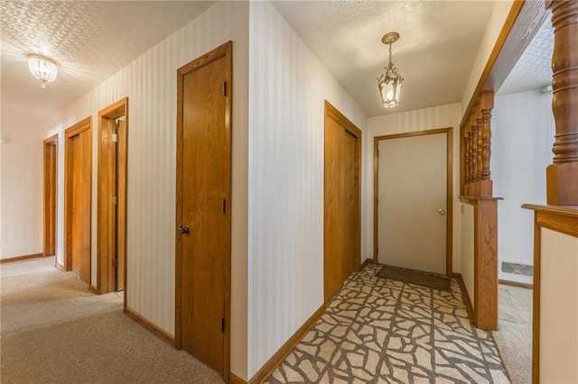 corridor with light carpet and a textured ceiling