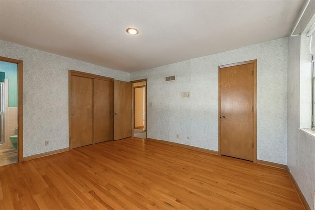 unfurnished bedroom featuring connected bathroom and light wood-type flooring