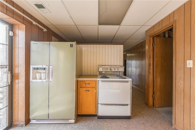 kitchen featuring fridge with ice dispenser, white electric range, wooden walls, and a paneled ceiling