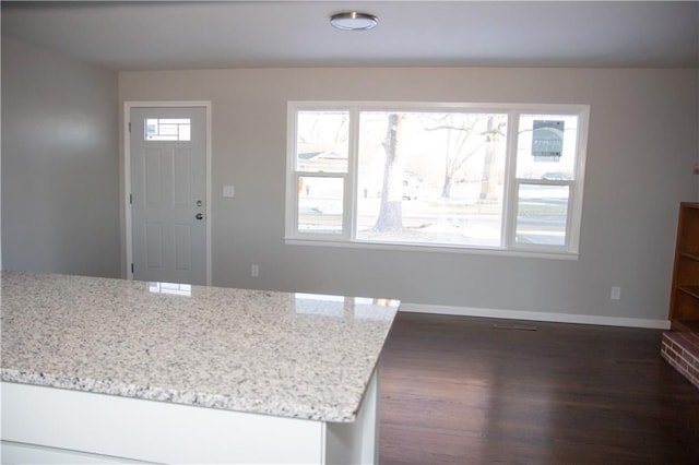 kitchen featuring dark wood-style floors, baseboards, and light stone countertops