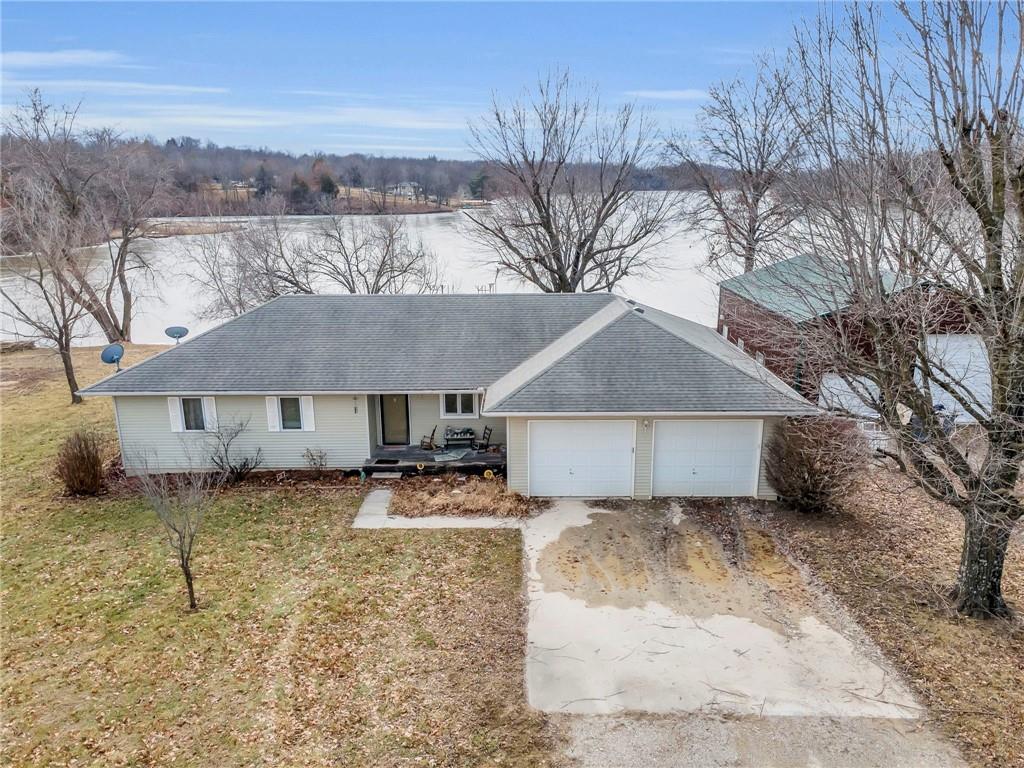 single story home with a garage, a front lawn, and a water view