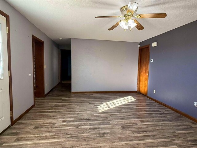 empty room featuring dark wood-type flooring, ceiling fan, and a textured ceiling