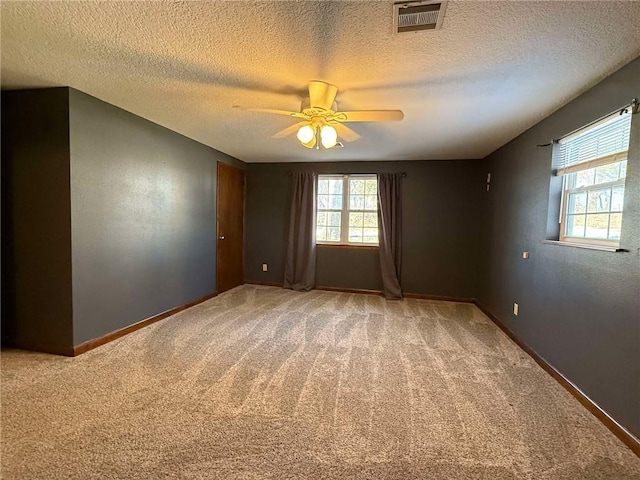 spare room with a textured ceiling, ceiling fan, and carpet