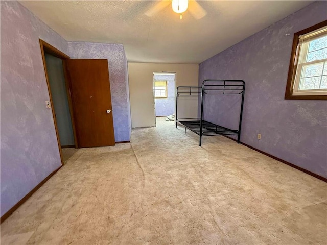 unfurnished bedroom featuring multiple windows, light carpet, and ceiling fan