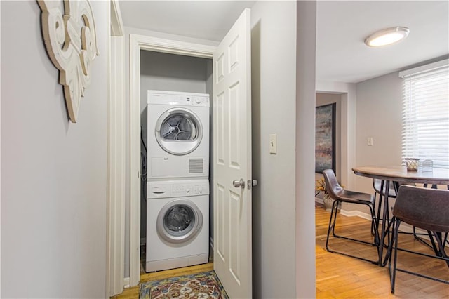 laundry room with stacked washing maching and dryer and light wood-type flooring