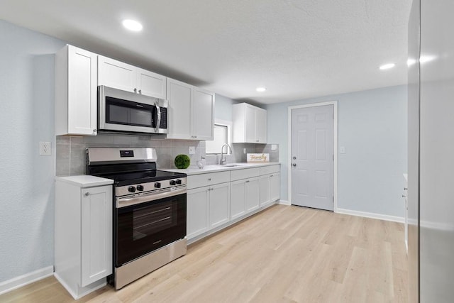 kitchen with sink, white cabinets, backsplash, and appliances with stainless steel finishes