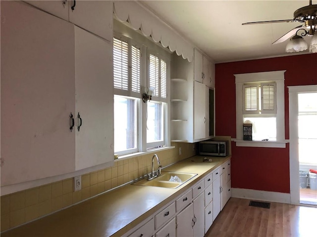 kitchen featuring white cabinets, light hardwood / wood-style flooring, a healthy amount of sunlight, and sink