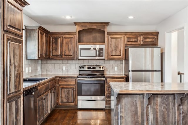 kitchen with dark hardwood / wood-style floors, stainless steel appliances, and tasteful backsplash