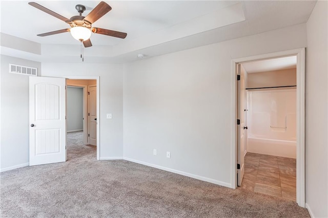 unfurnished bedroom featuring a raised ceiling, light colored carpet, and ceiling fan