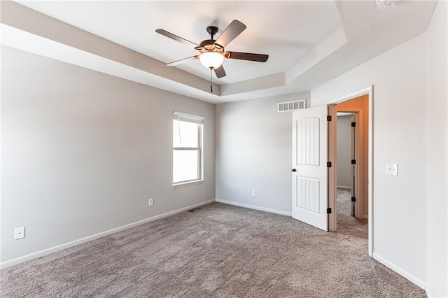 carpeted empty room featuring ceiling fan and a tray ceiling