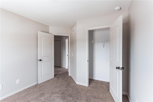 unfurnished bedroom with light colored carpet and a closet