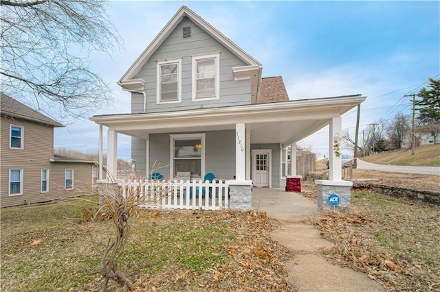 view of front facade with a porch, a shingled roof, and a carport