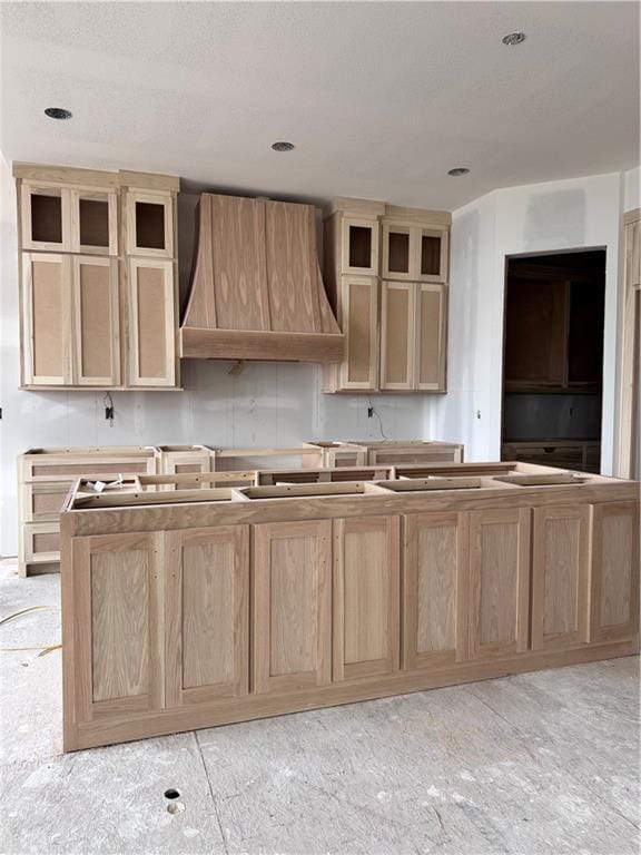 kitchen with a kitchen island, light brown cabinetry, and custom range hood