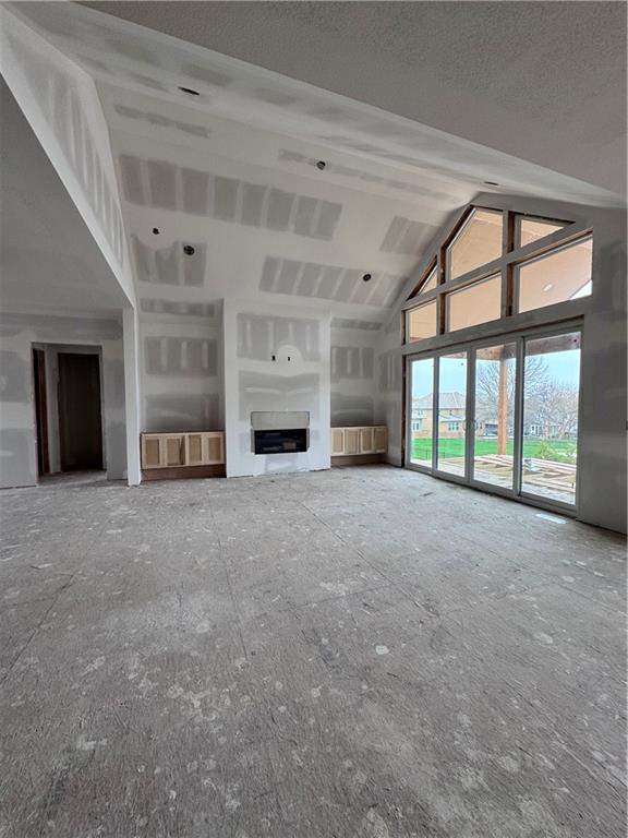unfurnished living room featuring a fireplace and high vaulted ceiling
